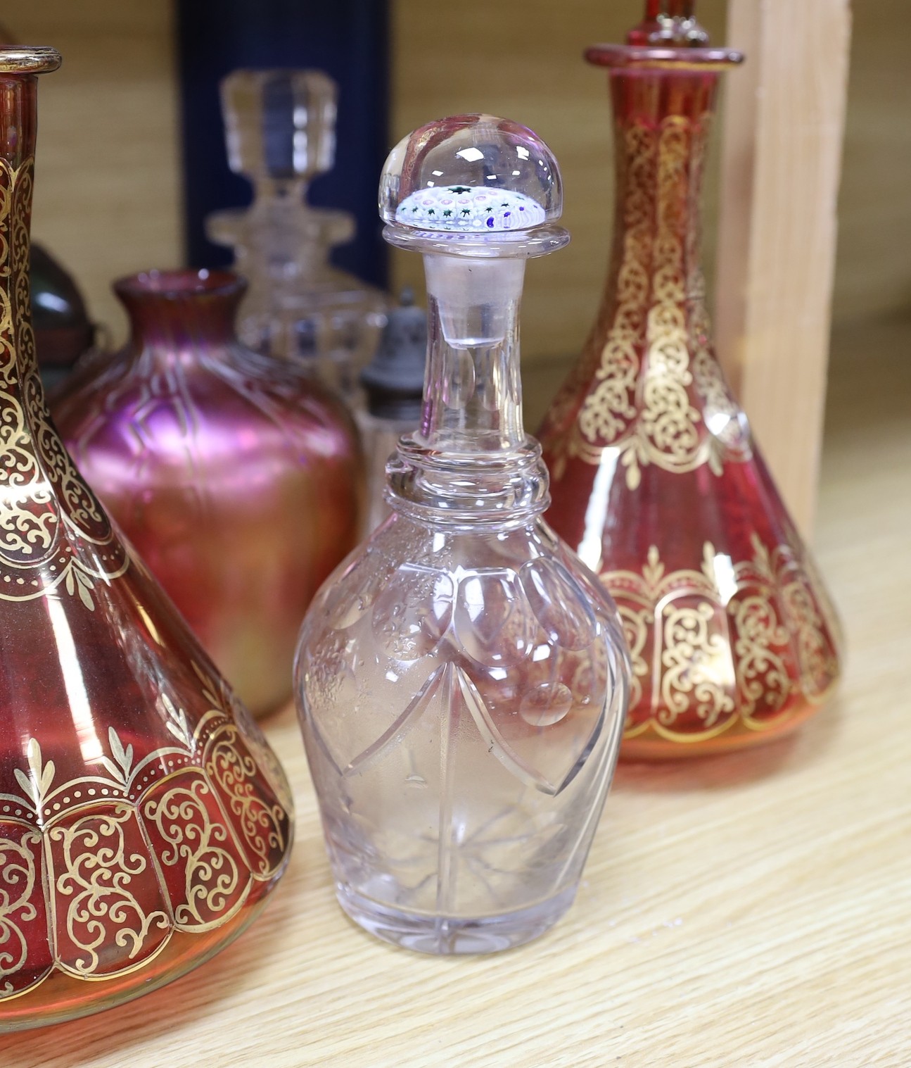 A pair of Bohemian gilded ruby glass decanters and stoppers, a Bohemian ‘millefiori paperweight’ stopper and associated decanter and mixed glass